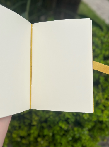 Caderno artesanal aberto mostrando folhas claras e marcador amarelo